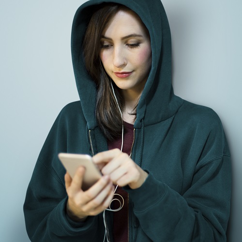 Beautiful young Ukrainian lady wearing a hoodie and looking attentively in her phone