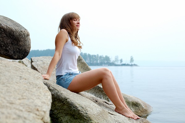 A young charming sexy Ukrainian girl sitting on a stone near the river in the forest