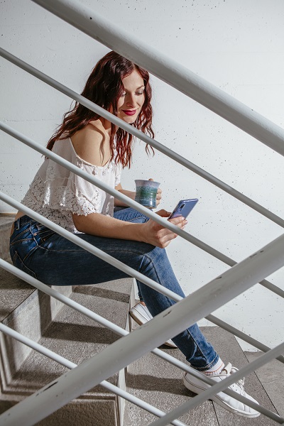 Ukrainian woman sitting on stairs looking at her messages on her smartphone