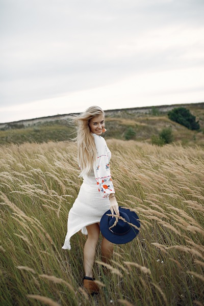 Beautiful elegant Ukrainian girl in an autumn wheat field posing for the camera in a nice dress