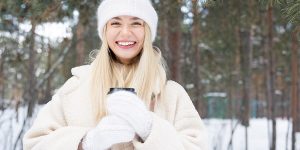 Happy young laughing Ukrainian blond female looking at you in a snowbound forest