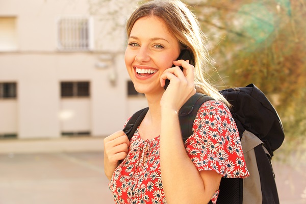 Happy young Ukrainian woman with a backpack talking on her cellphone while smiling