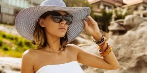 Pretty serious Ukrainian woman wearing a white hat and sunglasses during her summer vacation
